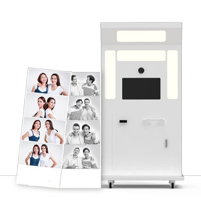 A white photo booth with a strip of black and white photos featuring smiling people.